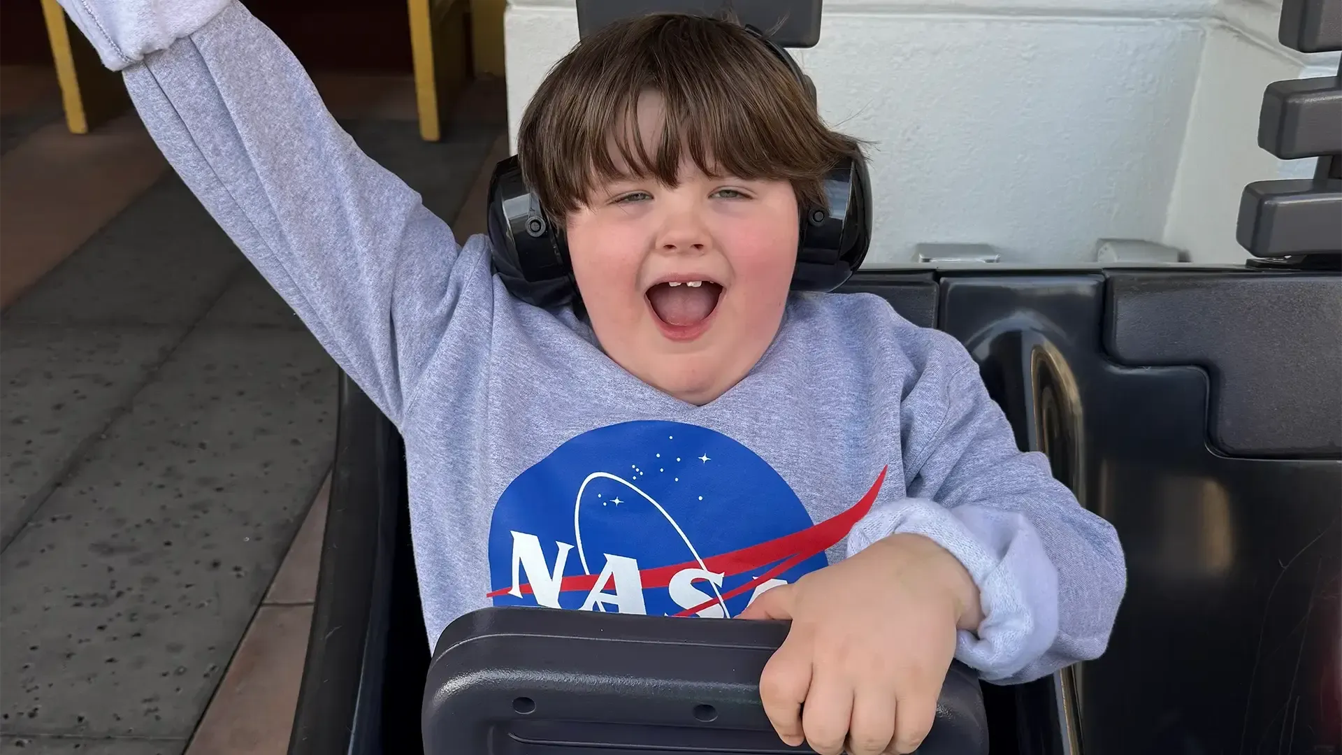 autistic child with noise canceling headphones on at a dinosaur amusement park