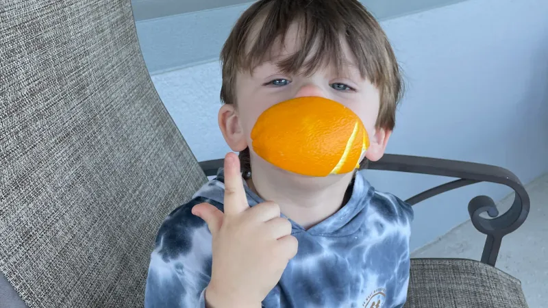 little autistic boyo with an orange wedge in his mouth