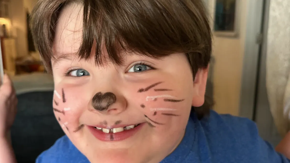 small boy with autism with face paint and a big smile